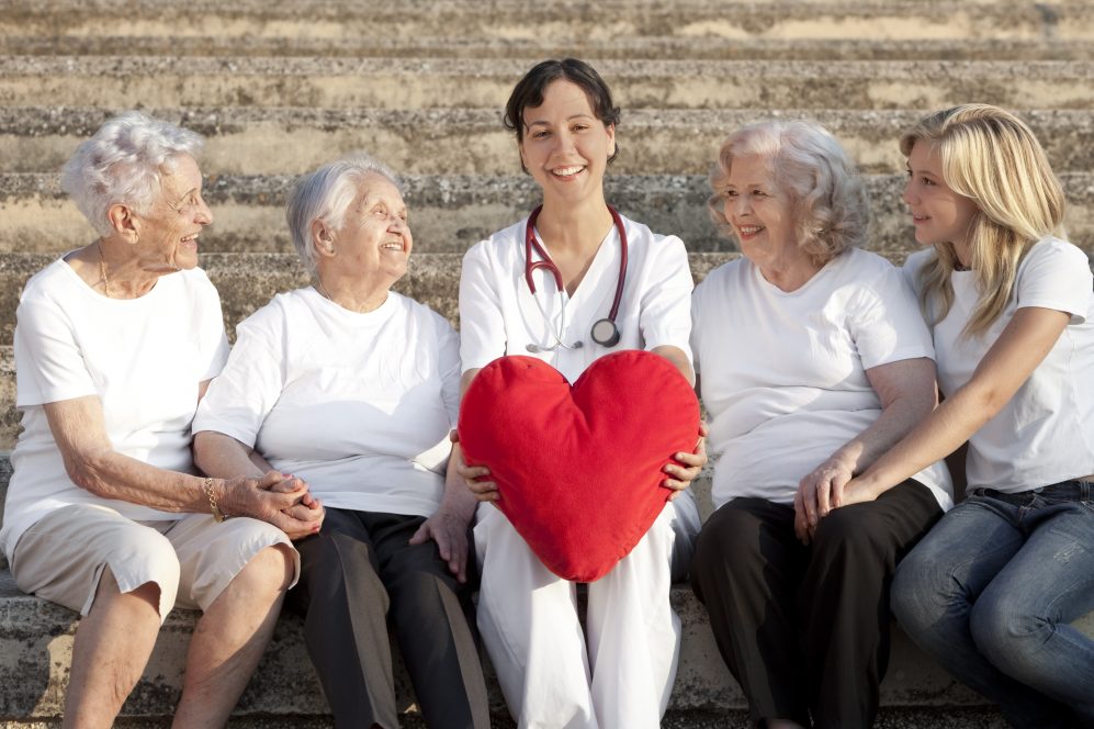 femme médecin avec un coussin cardiaque à la main avec trois femmes âgées et un petit-enfant, plus de personnes âgées