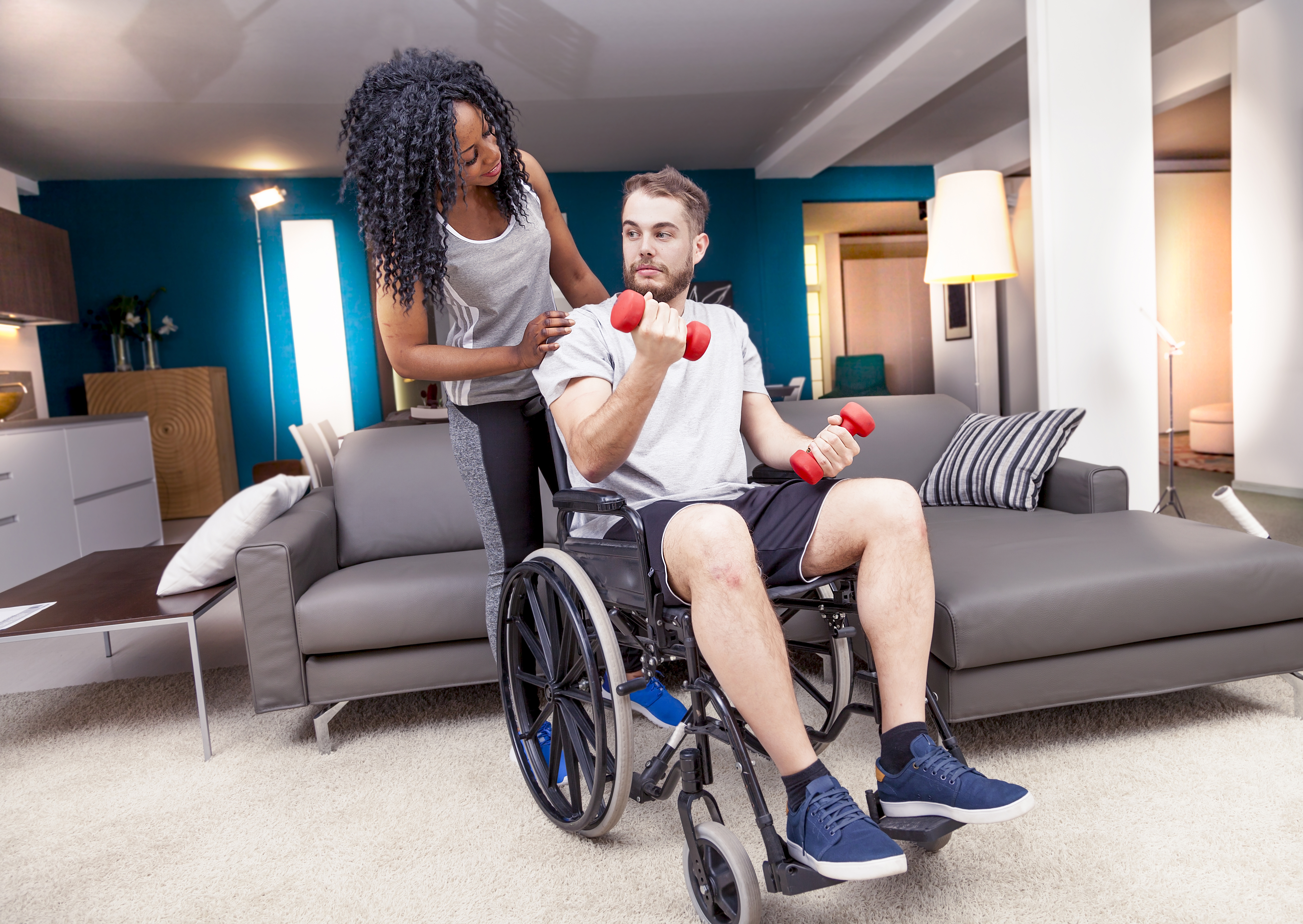 Woman helping man in wheelchair lift weights