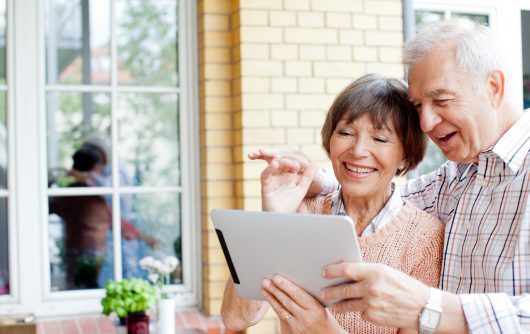 Couple de personnes âgées souriant à la tablette