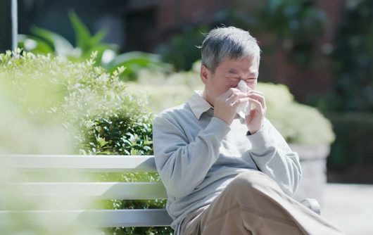 homme sur un banc de parc éternuant