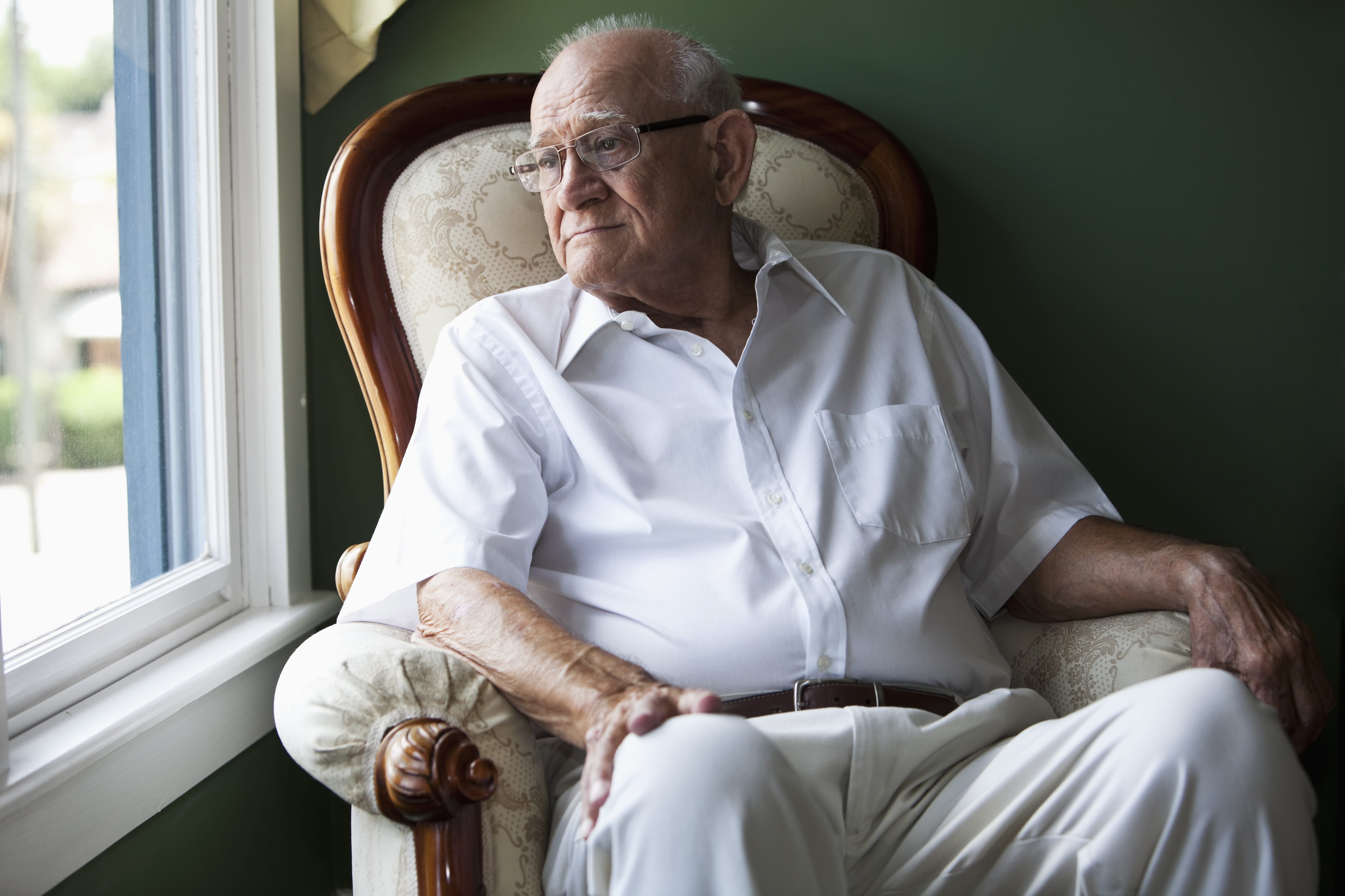 senior man sitting and looking out window