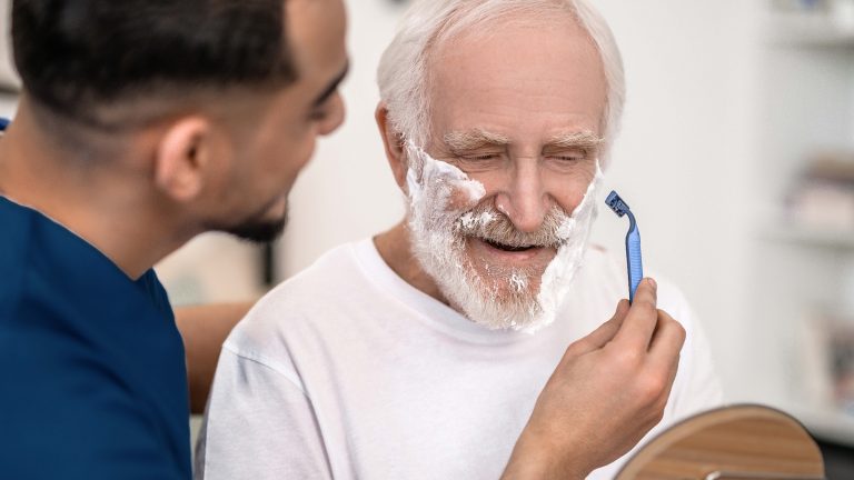 Caregiver helping senior man shave