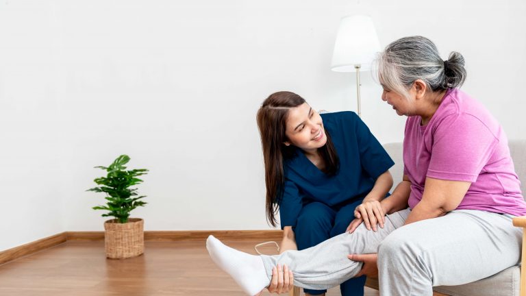 A caregiver providing foot care to a senior woman