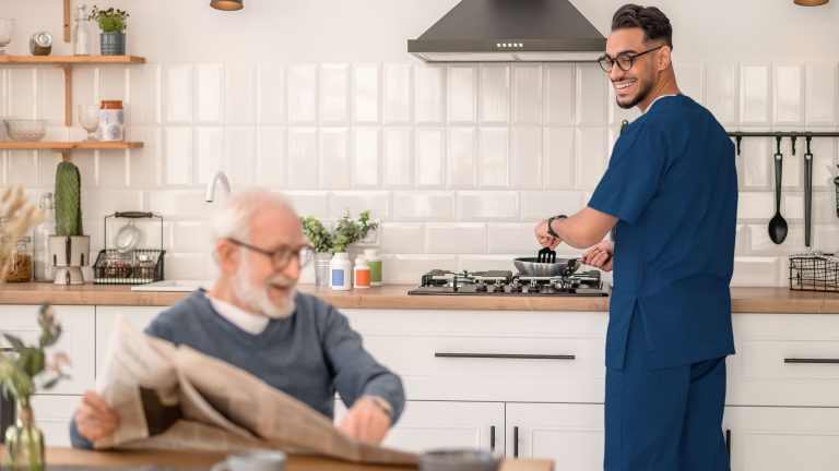 Caregiver cooking for senior client, assisting with meal preparation