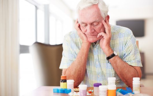 Senior man looking at lots of medication