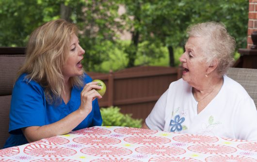 Speech therapist teaching senior woman patient