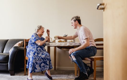Young man having tea with senior woman
