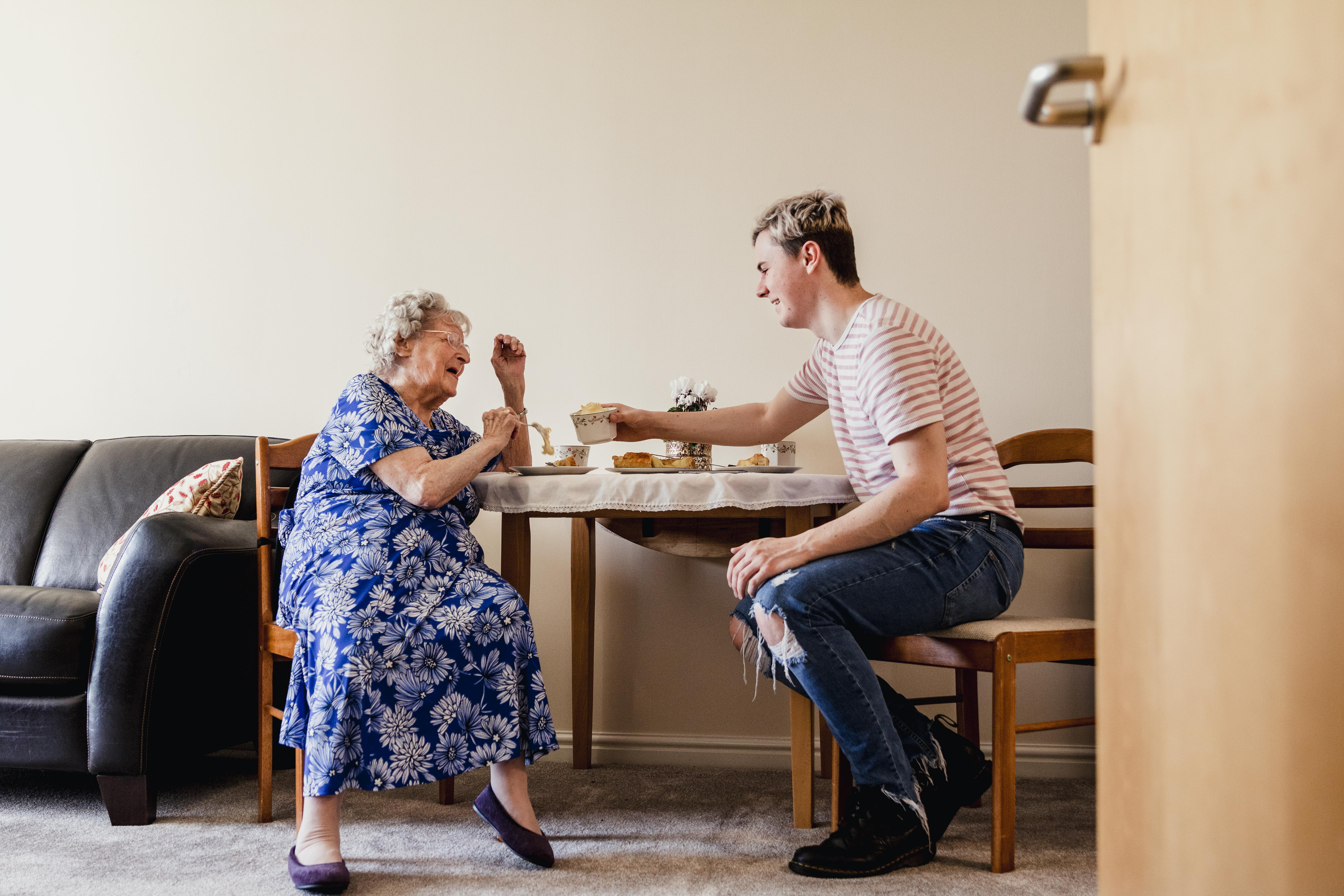 Young man having tea with senior woman