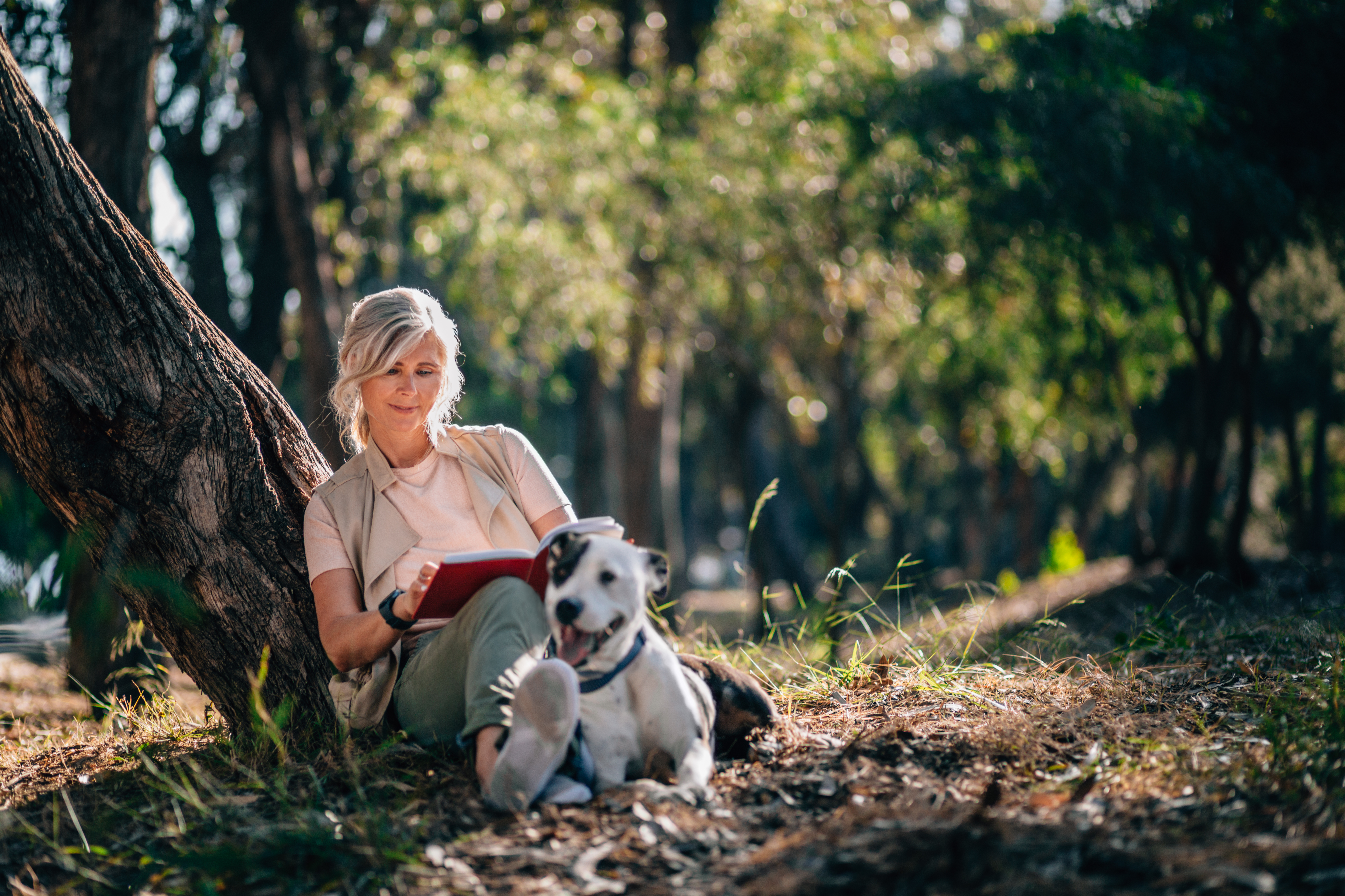 woman sitting in park reading with dog