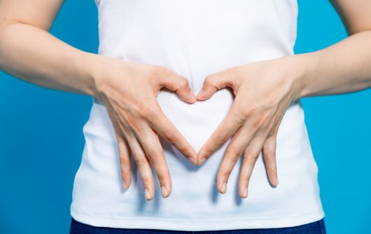 woman making heart shape with hands over stomach