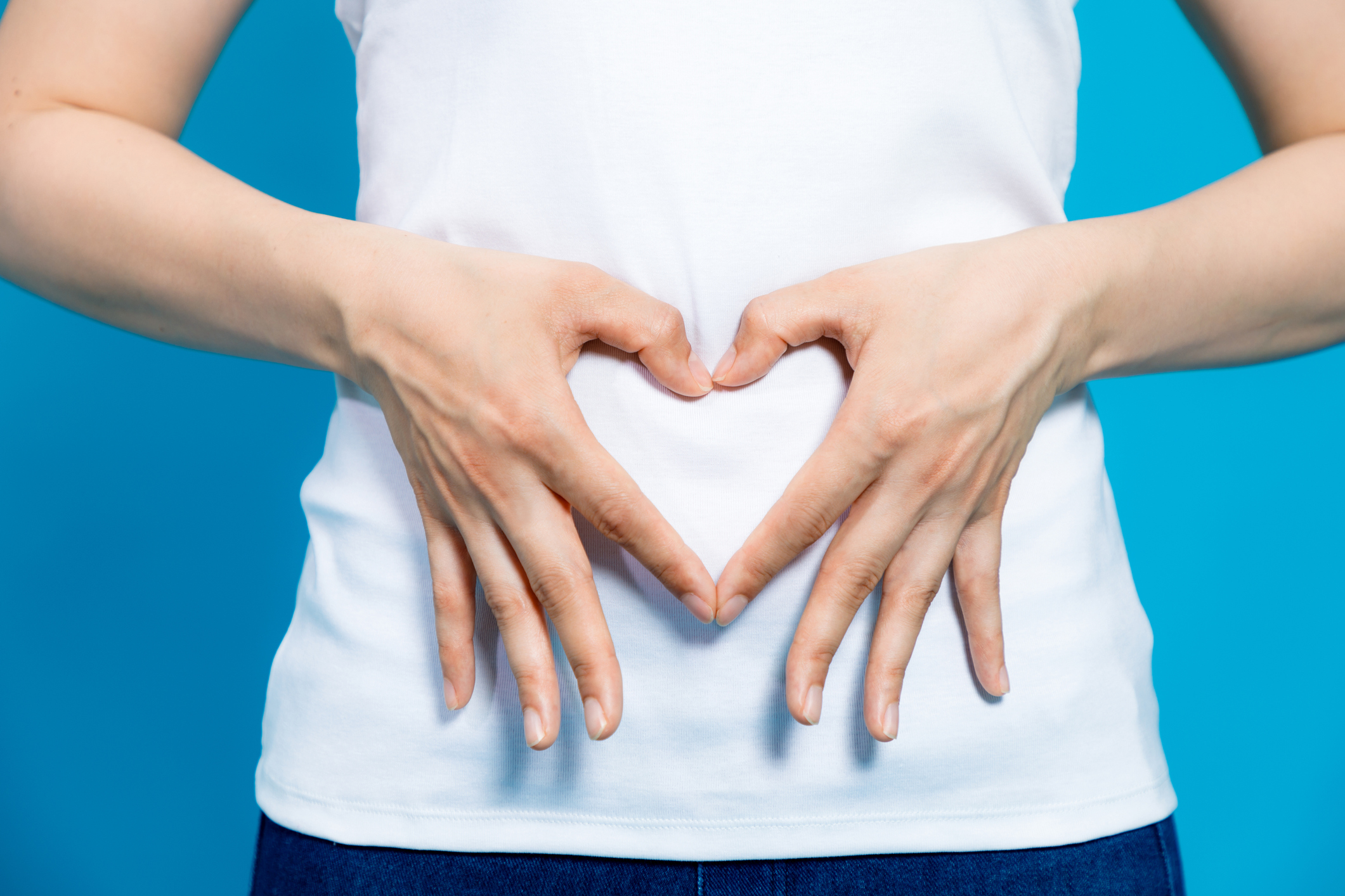 woman making heart shape with hands over stomach
