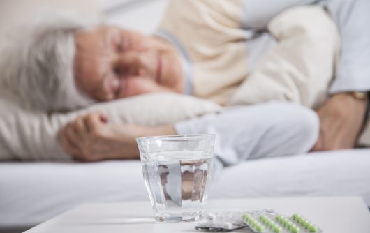 Femme dormant dans son lit à côté de la table de chevet avec des pilules et de l'eau