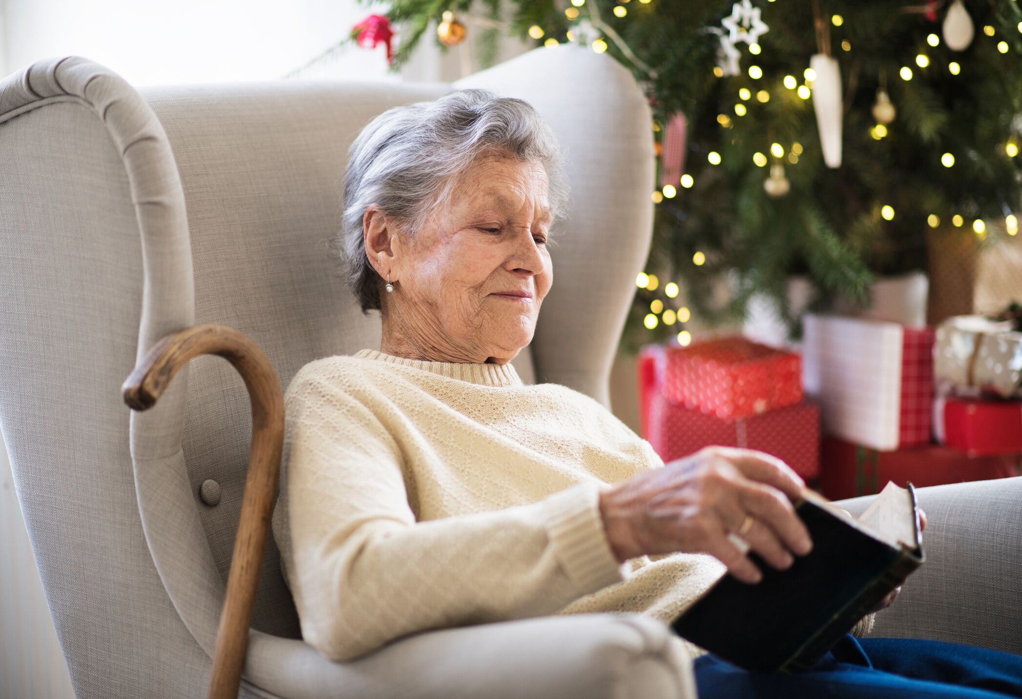 Senior woman sitting on couch avec livre de lecture de canne