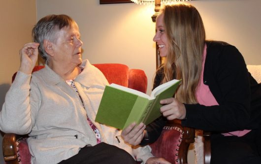 Daughter reading with elderly mother