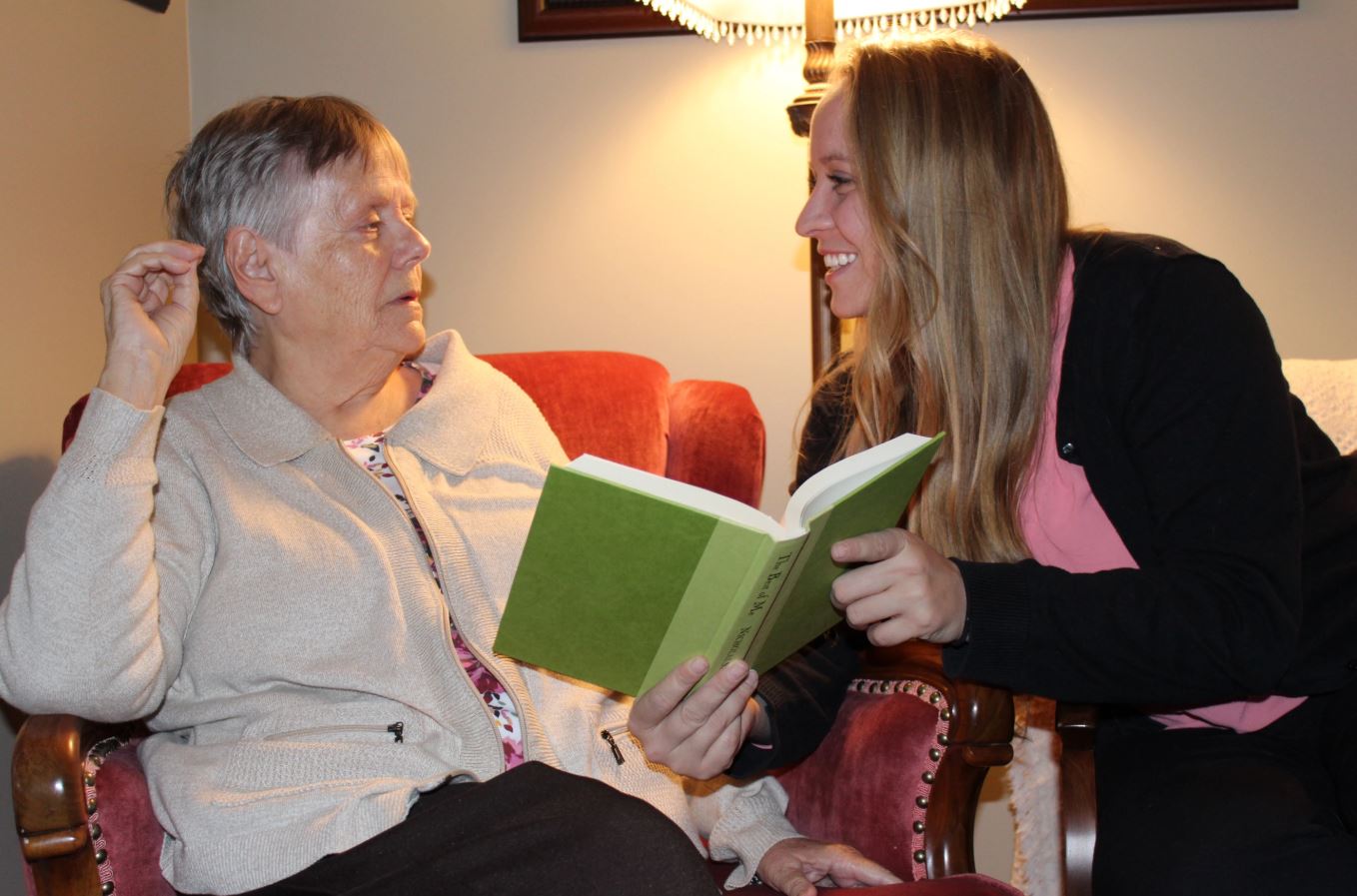 Daughter reading with elderly mother