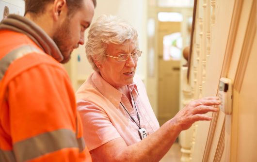 Senior woman setting up house alarm with young man