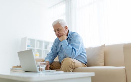 Homme lisant un ordinateur portable sur un canapé