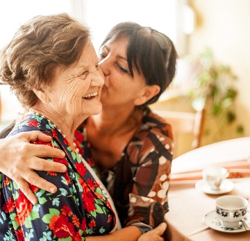 Woman kissing senior on cheek