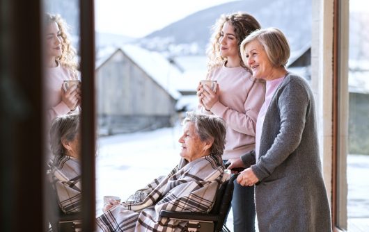 Grandmother, mother and daughter sitting on porch smiling