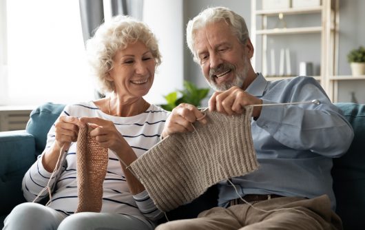 Senior couple knitting on couch