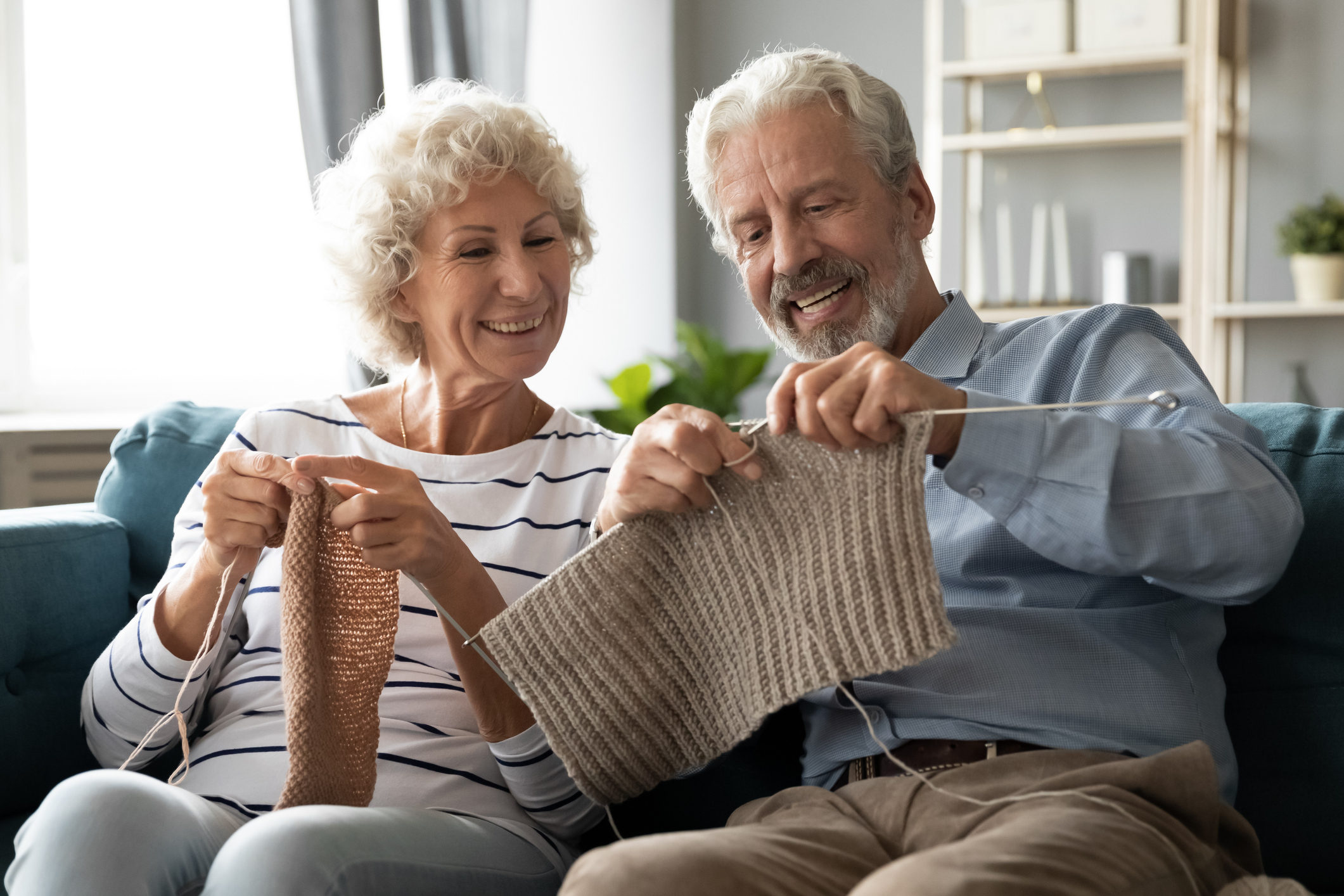 Senior couple knitting on couch