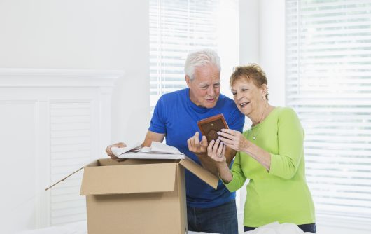 Senior couple packing cardboard box and looking at photographs