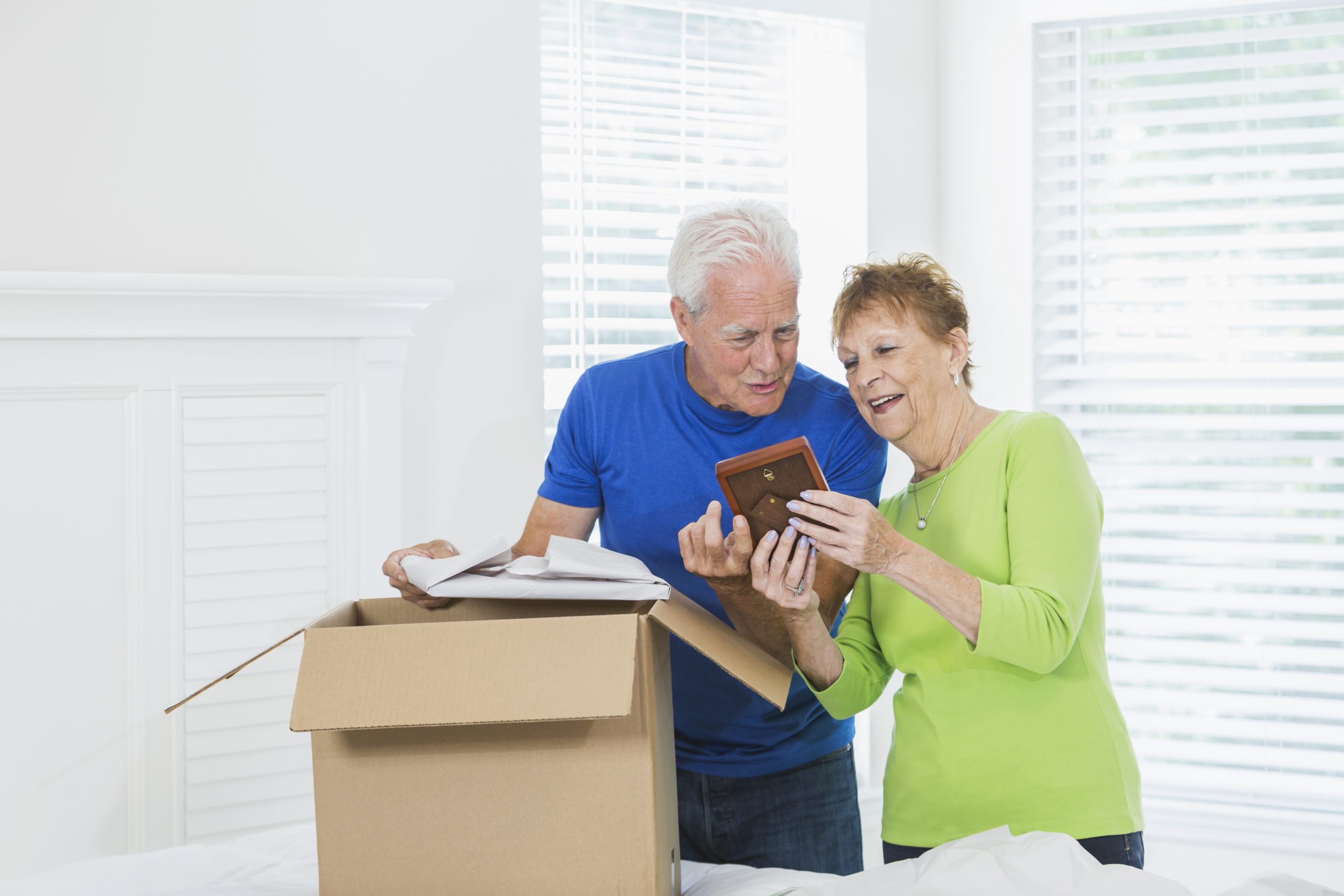 Senior couple packing cardboard box and looking at photographs