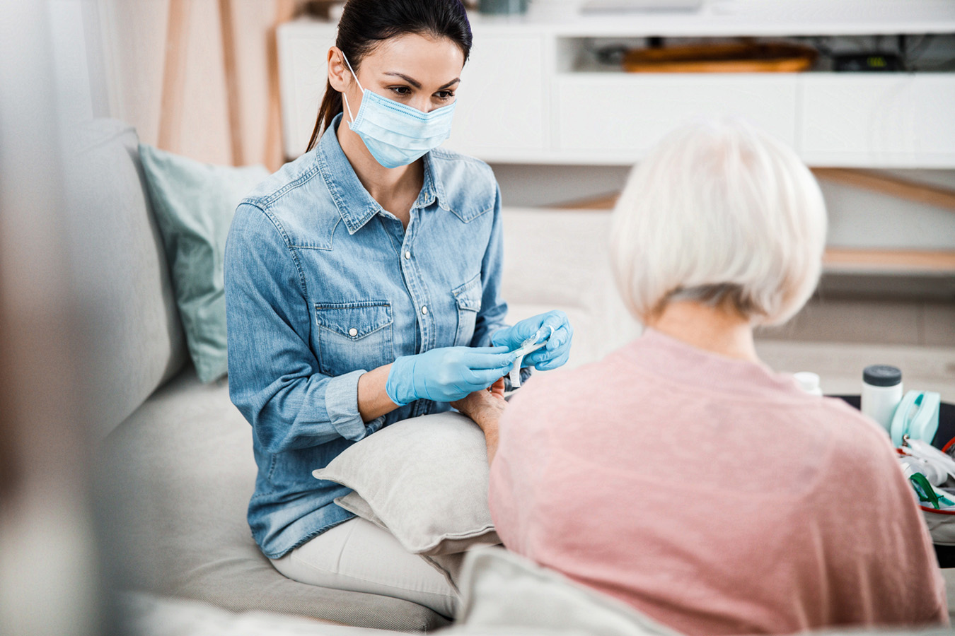 Compassionate nurse providing essential care and support to am elderly woman during the COVID-19 pandemic.