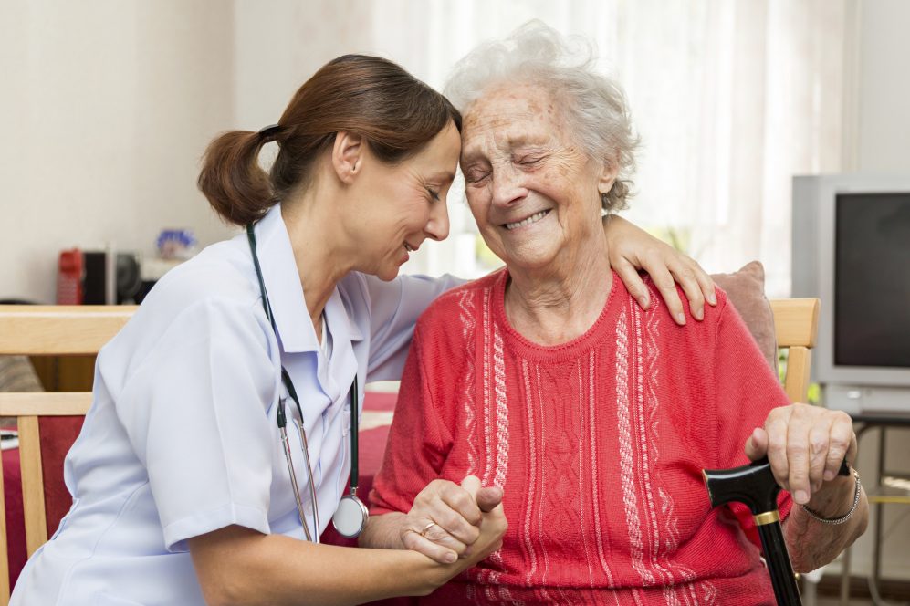 Caregiver embracing elderly woman