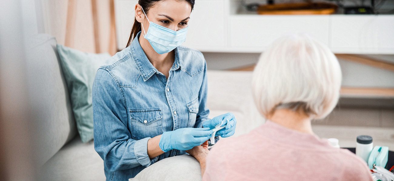 Femme au masque s'occupant d'un patient âgé