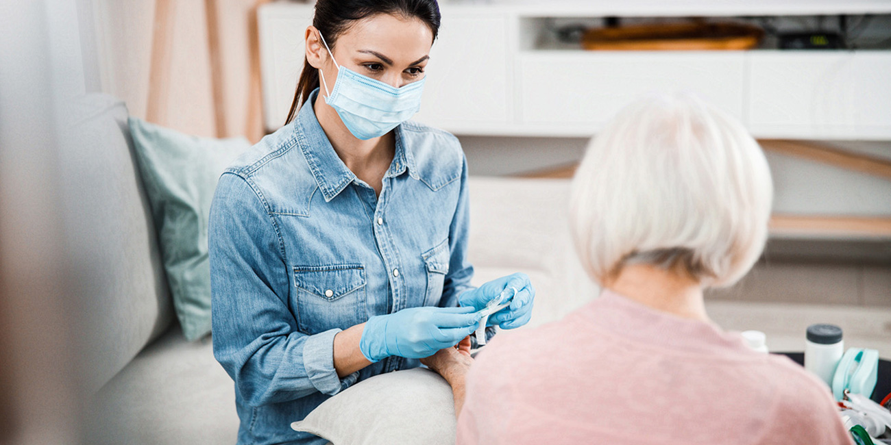 Woman in mask caring for senior patient