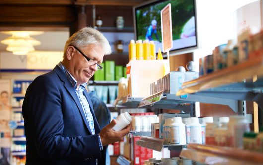 Homme adulte regardant des médicaments en pharmacie