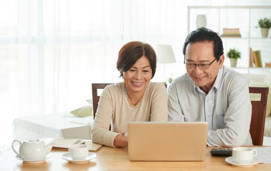 Senior couple smiling at laptop