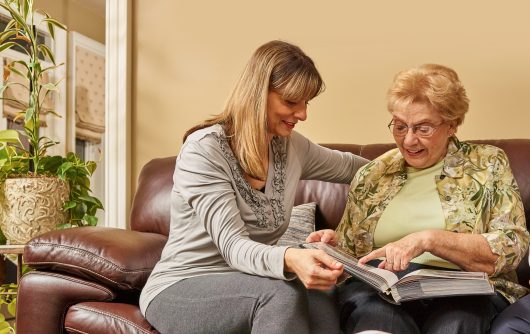 elderly mother and daughter looking through photo album