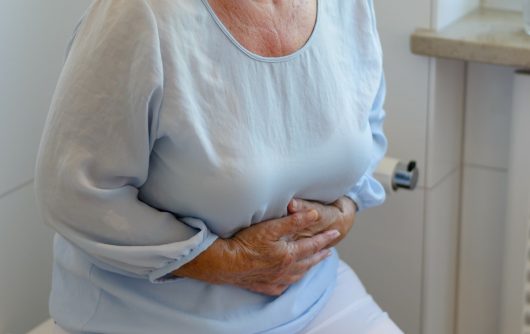 senior woman holding stomach in pain