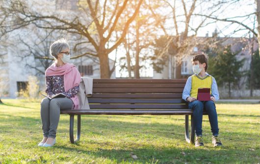 Grandmother and grandson social distancing on bench
