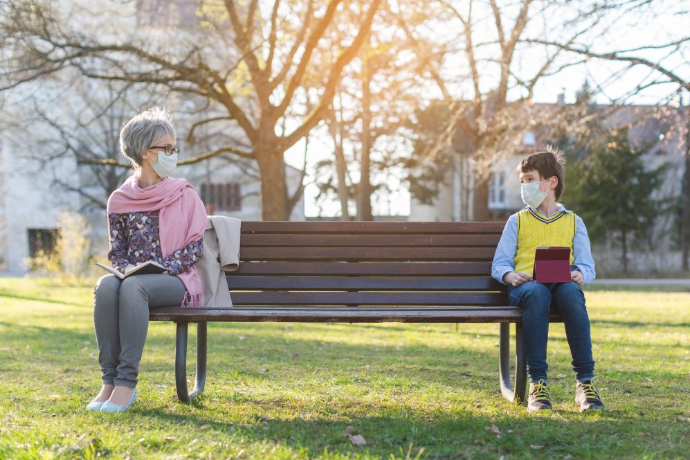 Grandmother and grandson social distancing on bench