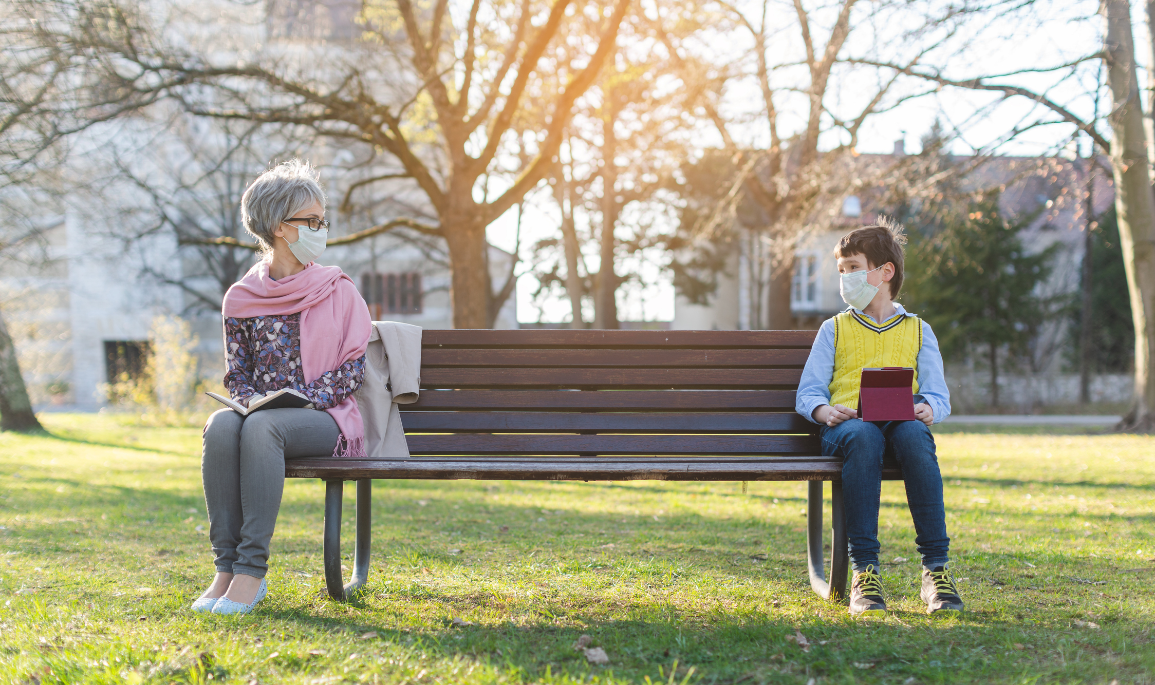 Grandmother and grandson social distancing on bench