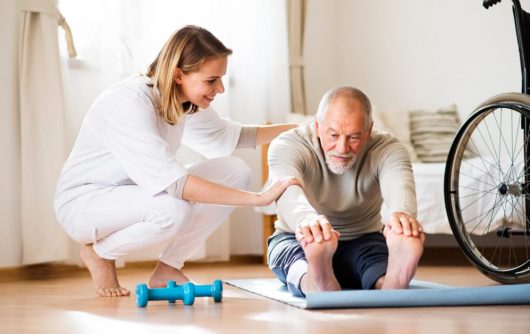 Physical therapist helping senior man stretch