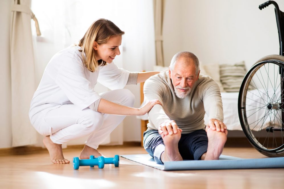 Physical therapist helping senior man stretch