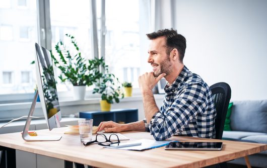 Homme adulte souriant à l'ordinateur