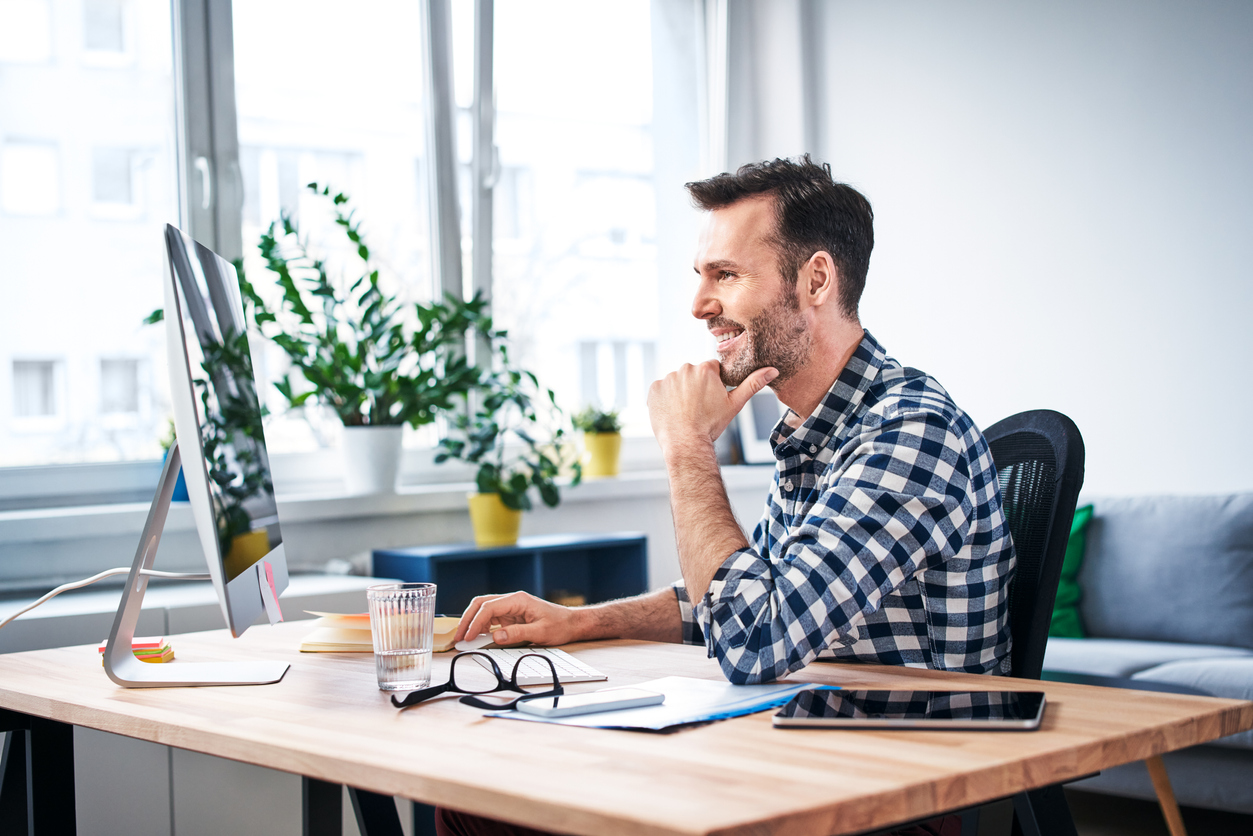 Homme adulte souriant à l'ordinateur