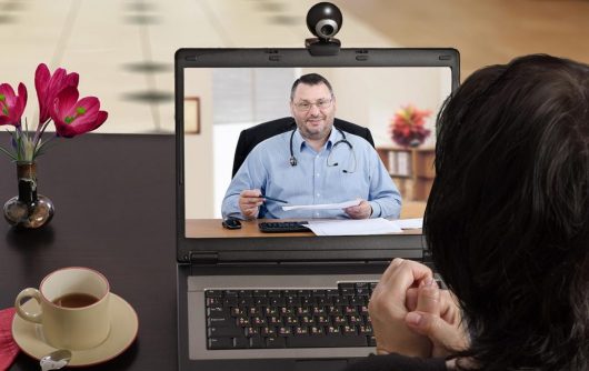 Person looking at laptop to virtual call with doctor