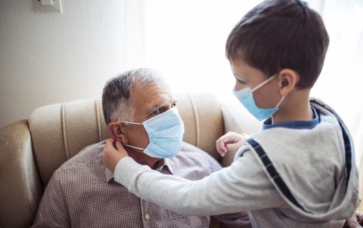 Enfant aidant un homme âgé à mettre un masque