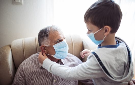 Child helping senior man put on mask