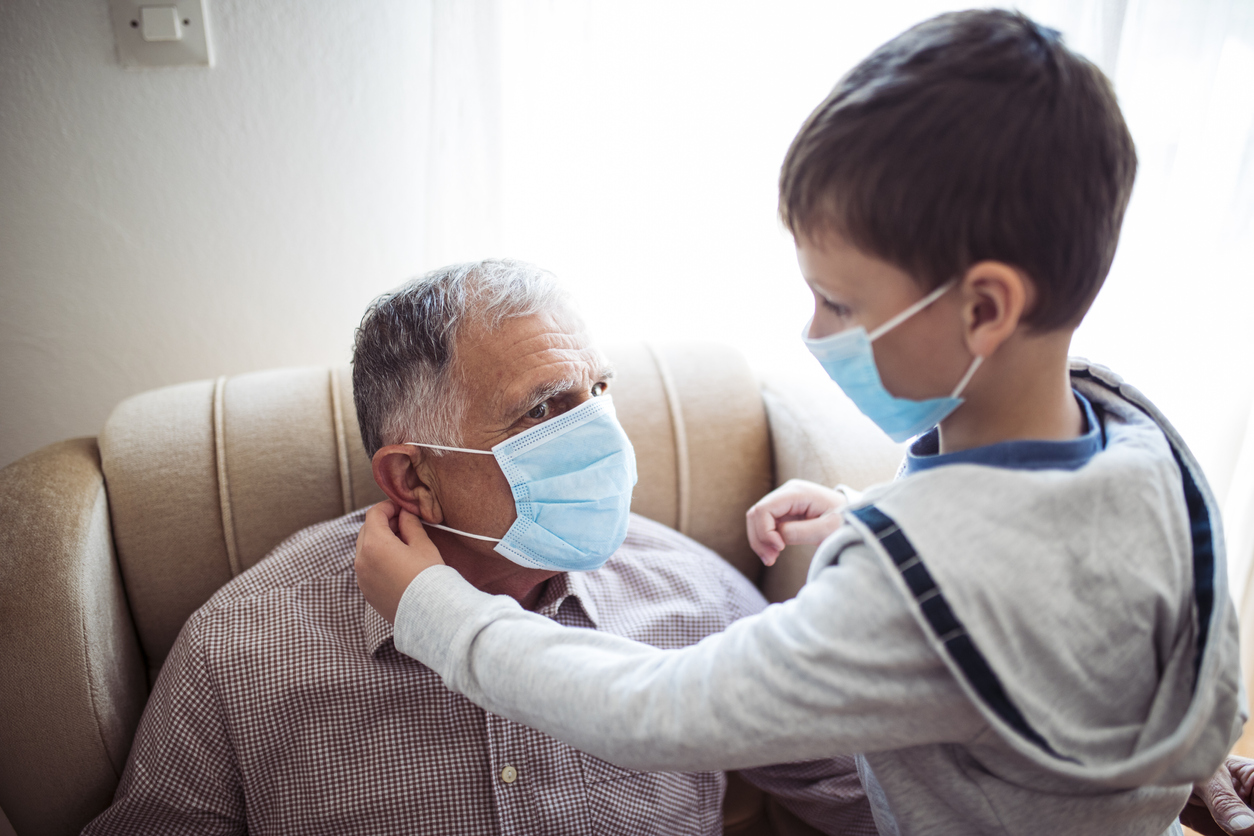 Child helping senior man put on mask