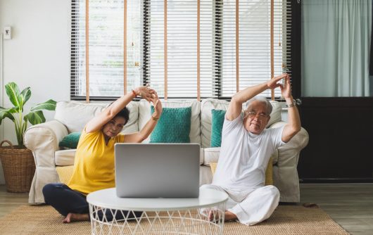 Couple de personnes âgées faisant du yoga devant un ordinateur portable