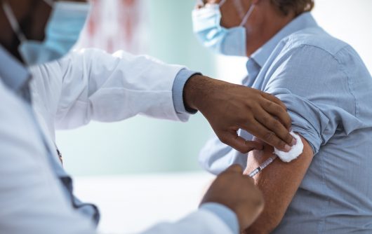 Doctor giving adult man a vaccine