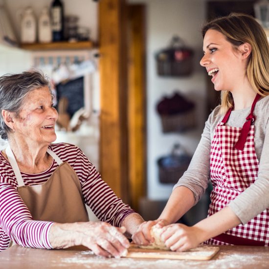 An elderly grandmother with an adult granddaughter at home, baking