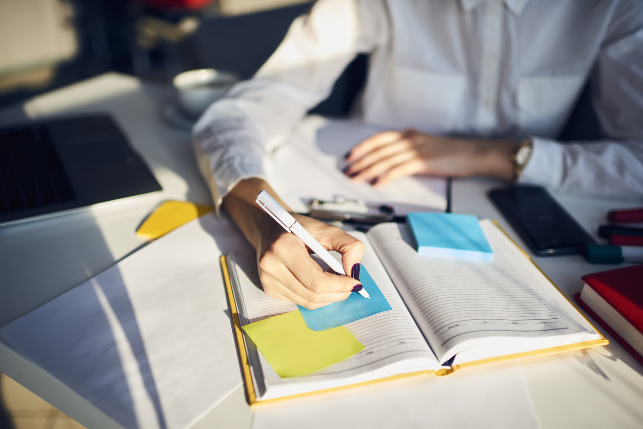 Professional woman writing on sticky note